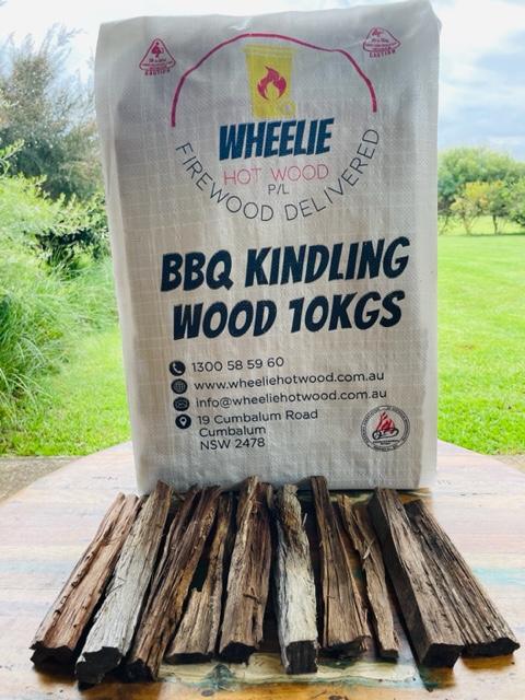 A burlap sack labelled 'BBQ Kindling Wood 10kg' from Wheelie Hot Wood filled with firewood pieces, displayed outdoors.  Wheelie Hot Wood delivers firewood in a wheelie bin in Northern Rivers NSW and Gold Coast, QLD. Bags of Firewood are also available for retail stores. 