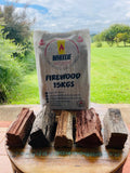 A bag labelled 'FIREWOOD 15KGS' from Wheelie Hot Wood with a backdrop of various hardwood pieces displayed on a wooden surface.